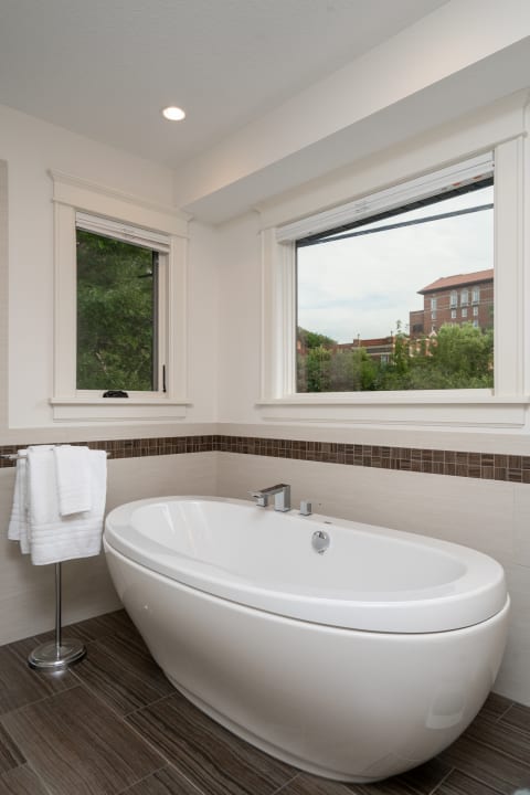 Stylish bathroom with a freestanding bathtub, chrome fixtures, and large windows overlooking greenery.