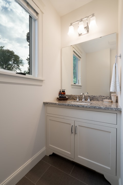 Contemporary bathroom featuring a granite sink area with a mirror and natural light.