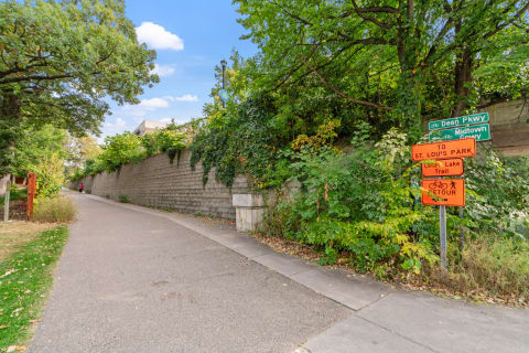 Biking and walking trail with signs and green foliage.