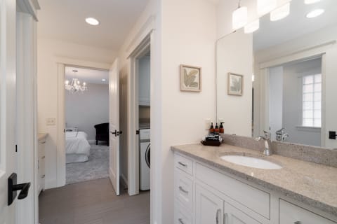 A modern bathroom with a granite countertop and a doorway to a bedroom.