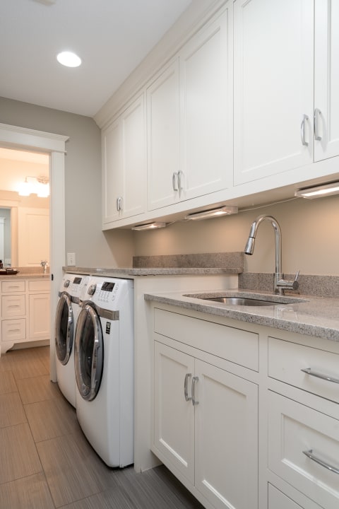 Modern laundry room with white washing machines and gray countertop.