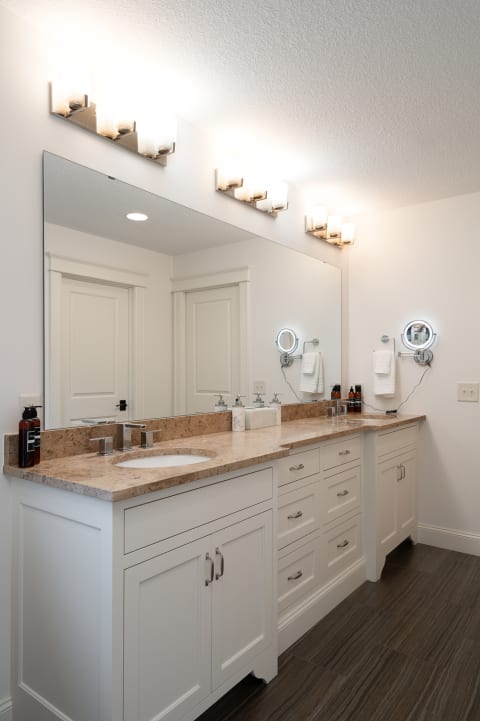 A modern bathroom with a large mirror, marble countertop, and decorative lighting.