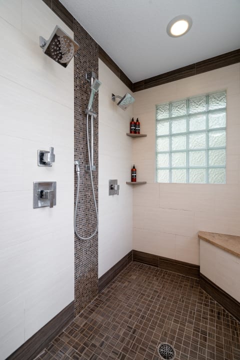 A contemporary shower with tile walls, glass block window, and built-in shelves.