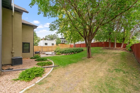 Backyard view showcasing a landscaped garden, seating area, and trees.