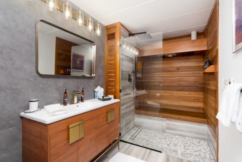 Modern bathroom with wooden vanity, large mirror, and glass shower enclosure.