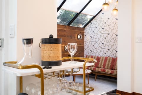 Stylish living room with a bar cart, striped couch, and geometric wall design.