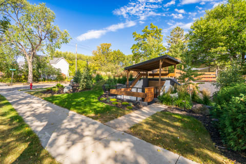 A suburban garden with a wooden deck, lush green landscaping, and a pathway.