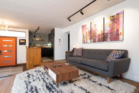 Cozy living room with grey sofa, colorful pillows, and modern art on the wall.
