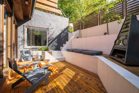 A contemporary outdoor terrace with gray chairs, an orange table, and a black outdoor stove.