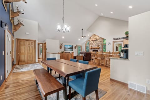 Interior of a rustic dining and living area with wooden furniture and deer mounts.