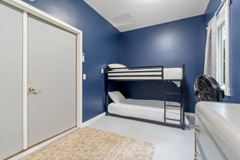 Cozy bedroom with a bunk bed, navy blue walls, and a window.