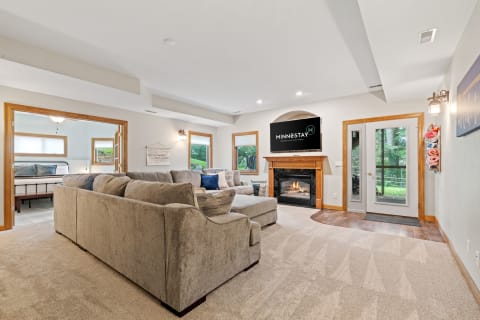 Inviting living room with a gray sectional couch, fireplace, and large windows.