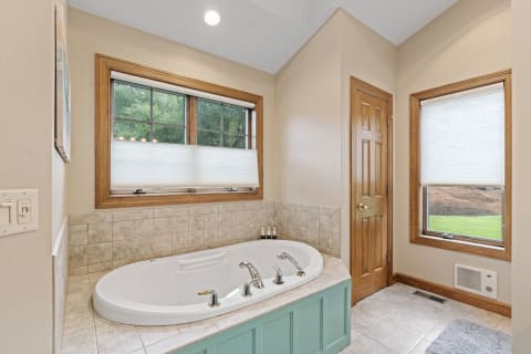 An elegant bathroom with a corner bathtub and large windows letting in light.