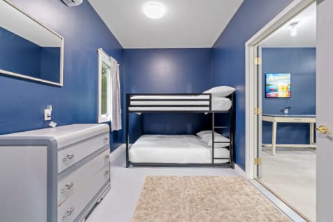 Cozy bedroom featuring a blue wall, bunk bed, and a chest of drawers.