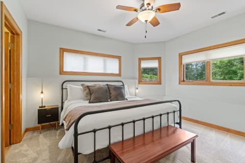 Cozy bedroom with a black metal bed, wooden accents, and large windows.