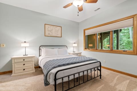 Cozy bedroom with a black metal bed and large window overlooking greenery.