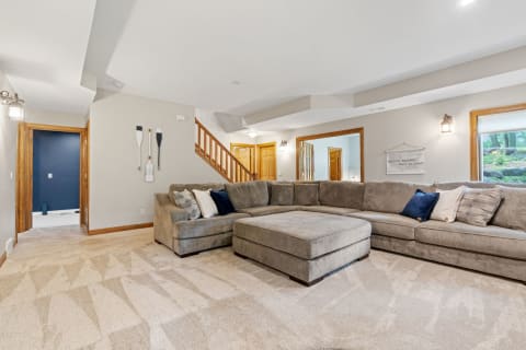 Cozy living room with a gray sectional couch and wooden decorative oars on the wall.