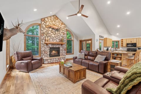 A spacious and inviting living room with a stone fireplace, leather sofas, and natural light.