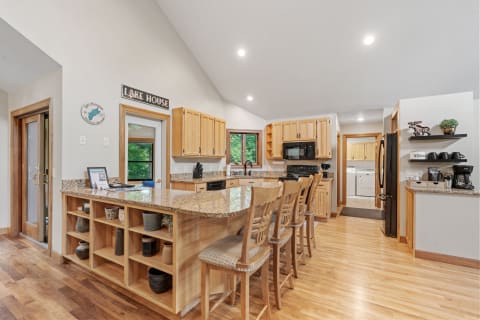 A warm kitchen featuring granite countertops and wooden cabinetry with bar seating.