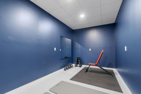 Home gym with blue walls, a red workout bench, and weights.