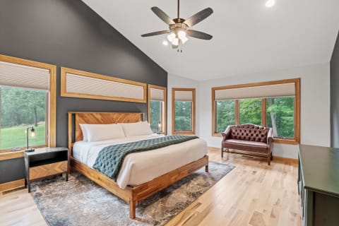 Stylish bedroom featuring a large bed, dark gray walls, and a leather loveseat near windows.