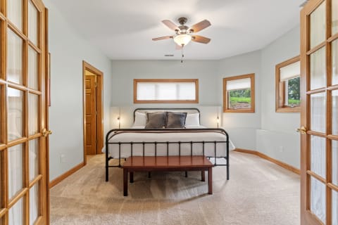 Cozy bedroom with a black metal bed, plush bedding, and a natural view through windows.
