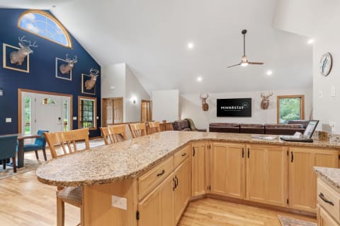 Interior view of a spacious room featuring a kitchen with granite countertops and rustic deer head decor.