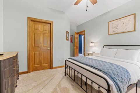 A well-decorated bedroom with a metal bed frame, blue blanket, and wooden furniture.