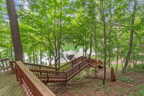 Winding wooden staircase through lush greenery leading to a dock on a lake.