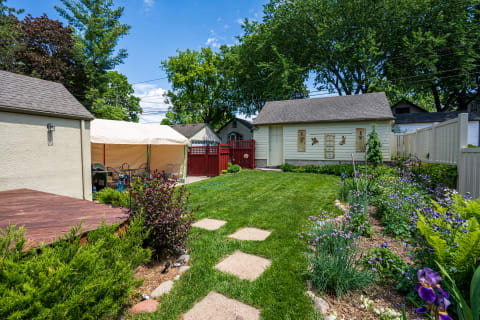 A backyard scene featuring a garden, a tent, and decorative fences.