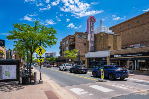 A busy urban street with the Edina Theater sign, shops, and vehicles.
