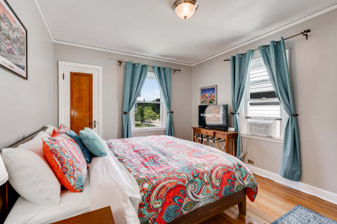 Cozy bedroom with a paisley comforter, aqua curtains, and a flat-screen TV.