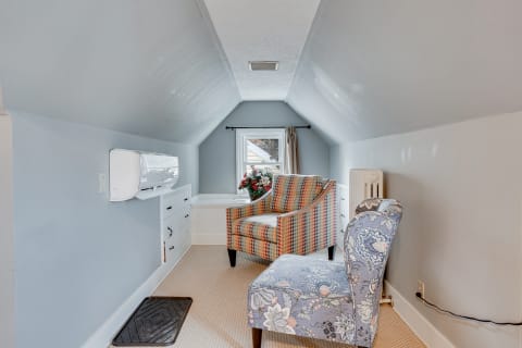 Cozy attic interior with patterned chairs and window.