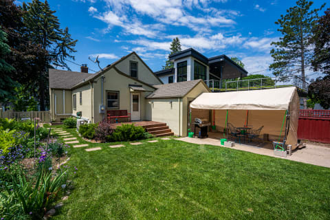 Backyard view with a house, garden, and a tent seating area.
