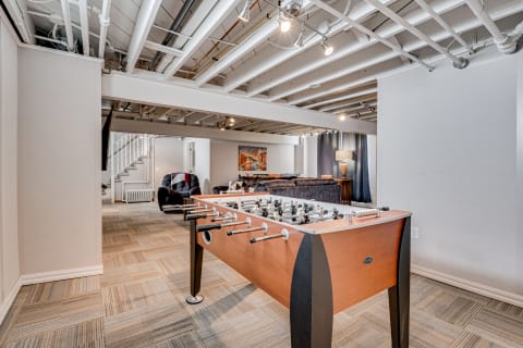 Basement game room with foosball table and plush seating area.