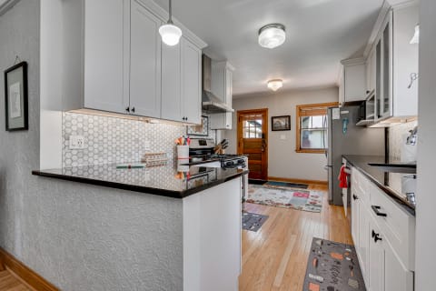 A cozy kitchen featuring white cabinets, granite countertops, and hexagonal tile backsplash.