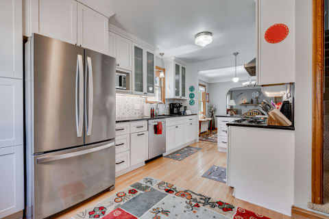 A spacious, modern kitchen with stainless steel appliances and colorful rugs.