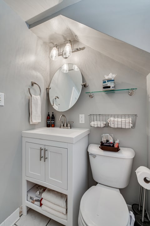 Compact modern bathroom with a white vanity, round mirror, and neatly arranged towels.