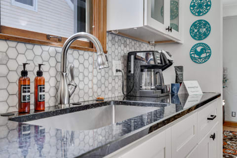 Modern kitchen counter with stainless steel sink, amber soap bottles, and coffee maker.