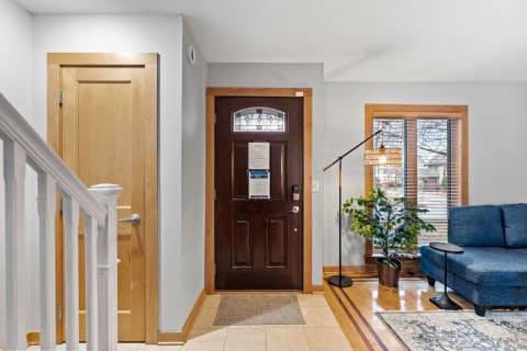 The entrance of a home with a wooden door, blue sofa, and indoor plant.