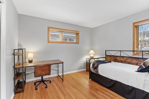 A modern bedroom with a bed, desk, and decorative details.