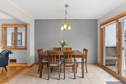 A charming dining room featuring a wooden table, chairs, and a brick wall.