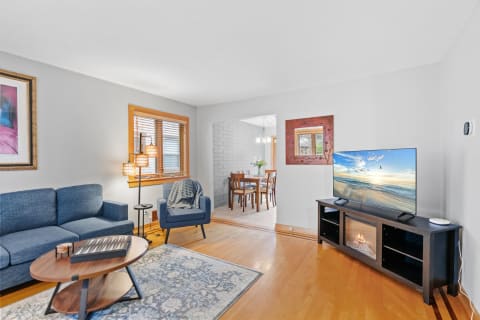 A cozy living room with a blue sofa, wooden coffee table, and a modern TV setup.