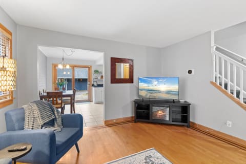 Cozy living room featuring a blue armchair, television, and open pathway to dining area.