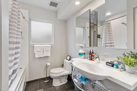 A contemporary bathroom with a bathtub, toilet, sink, and neatly arranged toiletries.