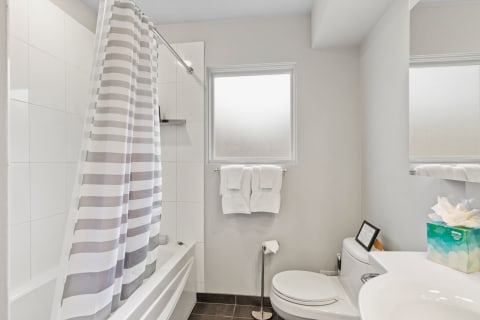 Modern bathroom with bathtub, shower curtain, and white towels.