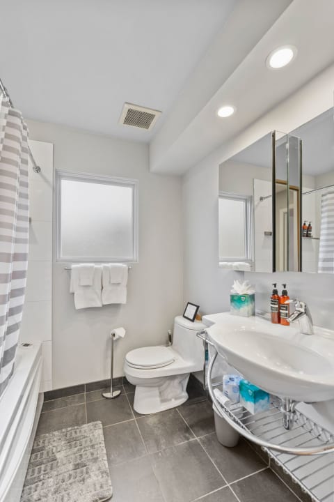 A contemporary bathroom with a white sink, mirror, and striped shower curtain.