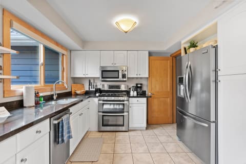 Contemporary kitchen featuring white cabinetry, a stainless steel refrigerator, and a large window.