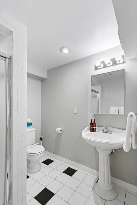 Bright bathroom featuring a pedestal sink and a glass shower.