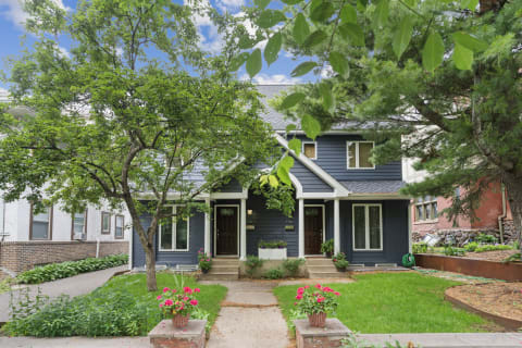 Front view of a stylish duplex with a blue exterior and flower pots.